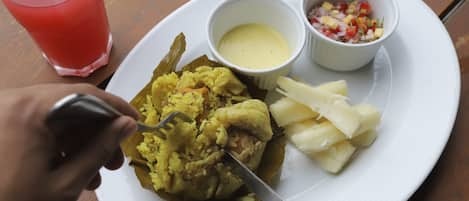 A plate with rice, potatoes, and two small bowls of sauce on a wooden table.