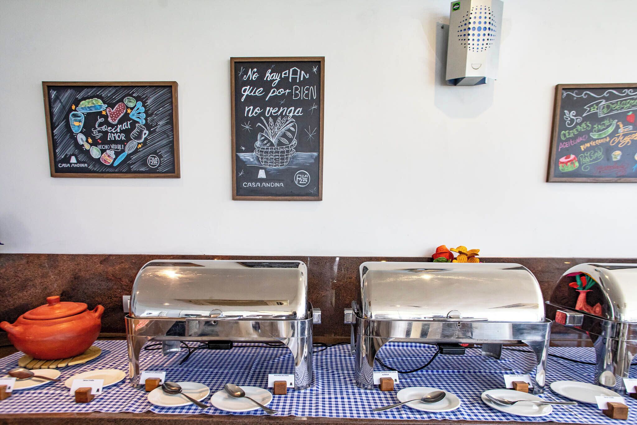 Montaje de un bufé de desayuno con dos estaciones de comida caliente de servicio libre, una pizarra con un mensaje y un tazón decorativo en la barra.
