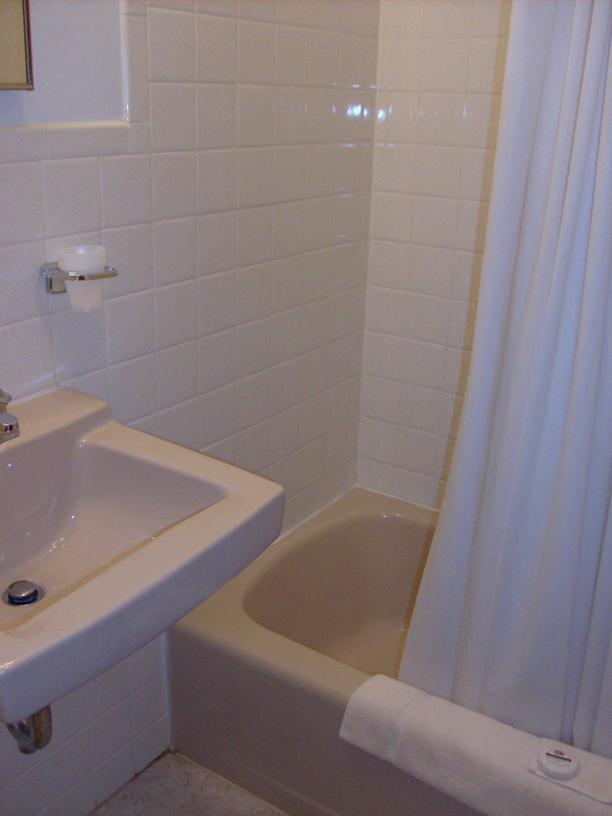 Une salle de bain avec un lavabo blanc, une baignoire et un rideau de douche.