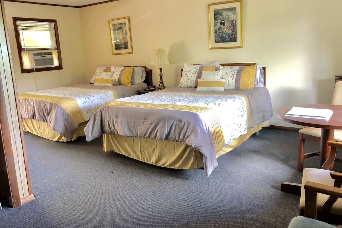 Une chambre d’hôtel avec deux lits, un bureau et une chaise.