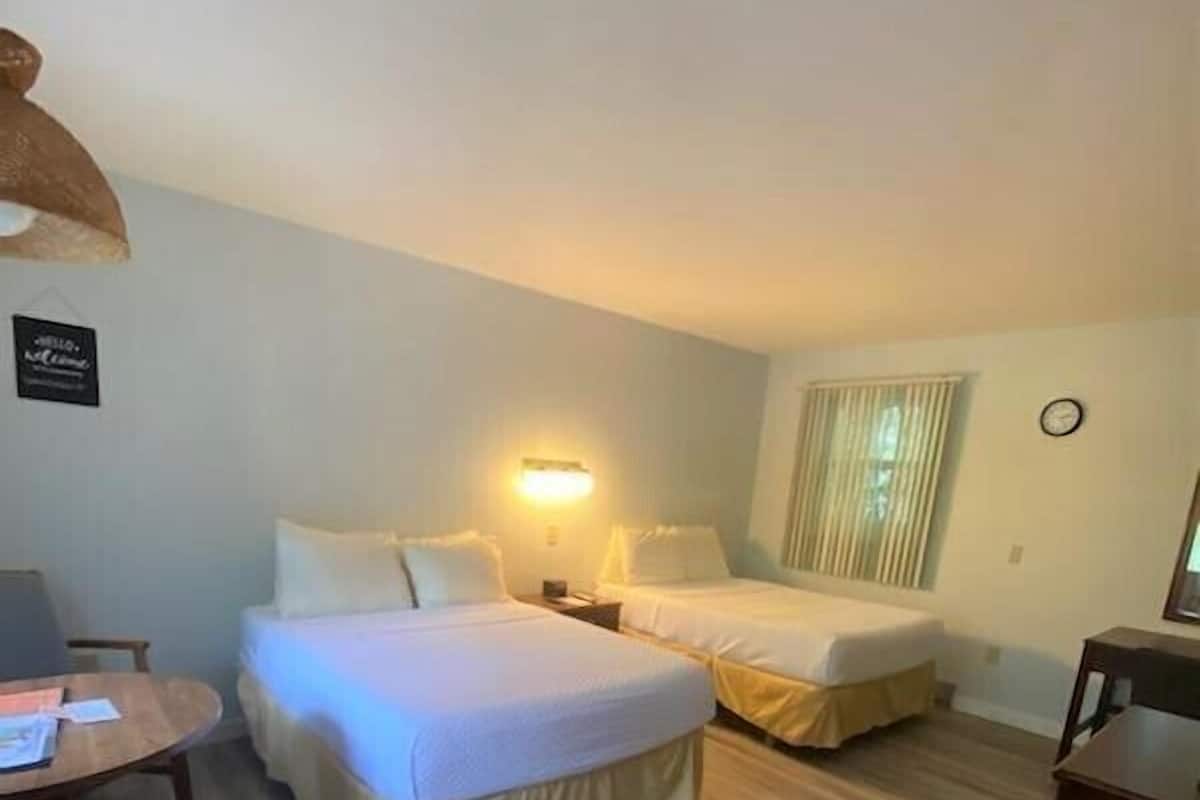 Une chambre d’hôtel avec deux lits, un bureau et une chaise.