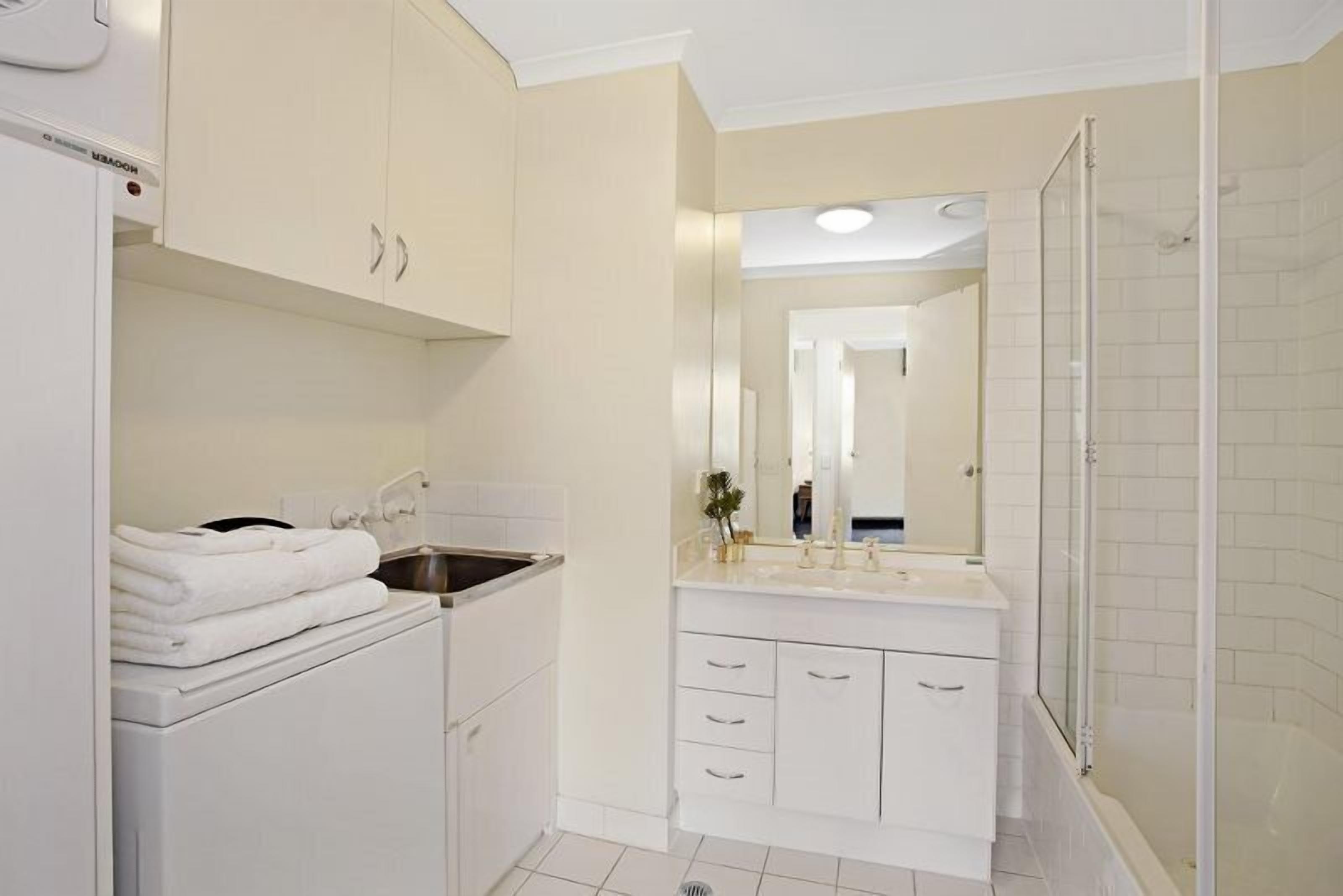 A modern bathroom with a sink, mirror, and shower.