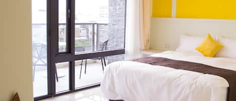 Una habitación de hotel con una cama grande, una araña de cristal, vistas a través de un ventanal corredero y una escultura de gato.