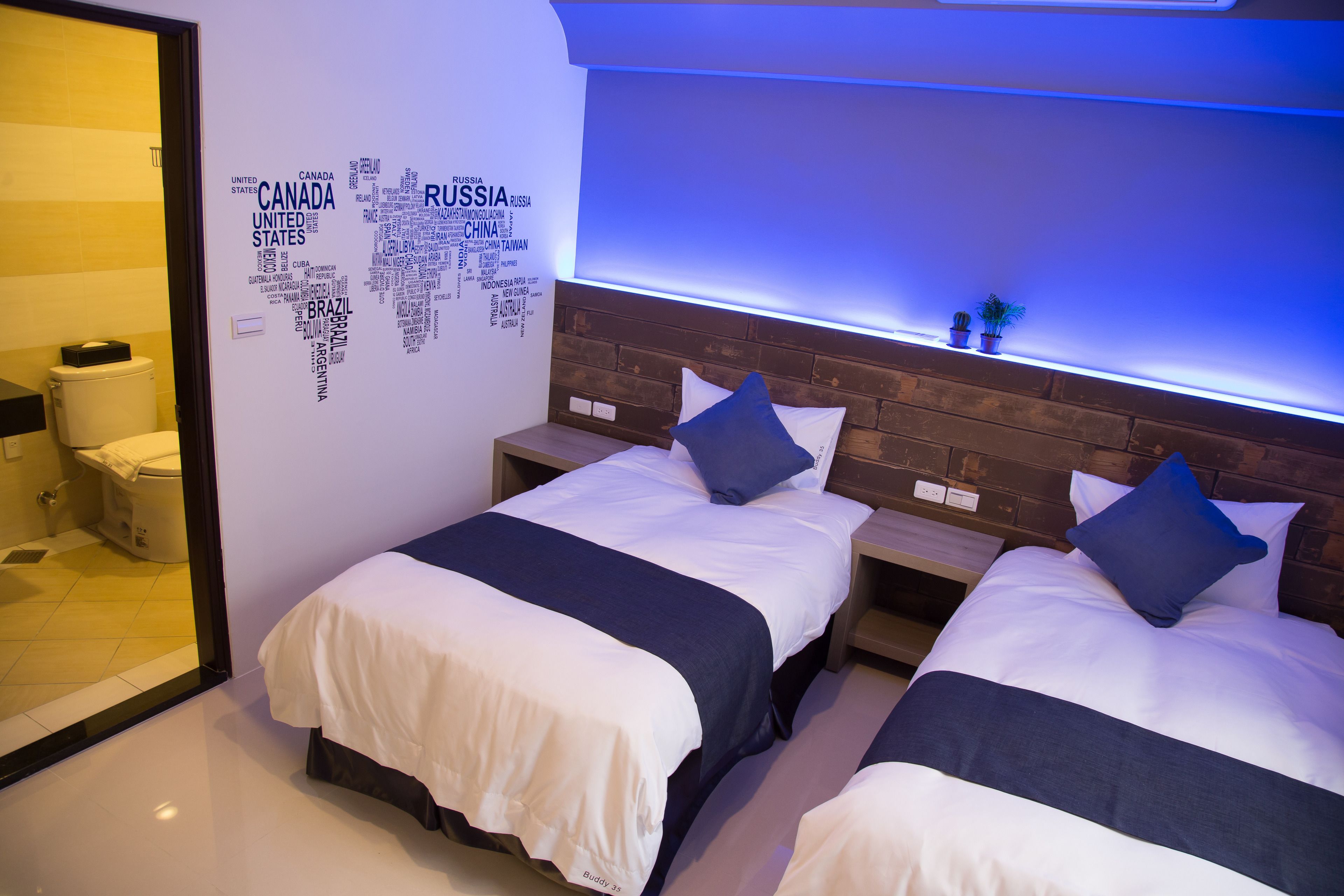 Habitación de hotel con dos camas, un baño y una pared decorada con un mapa del mundo.