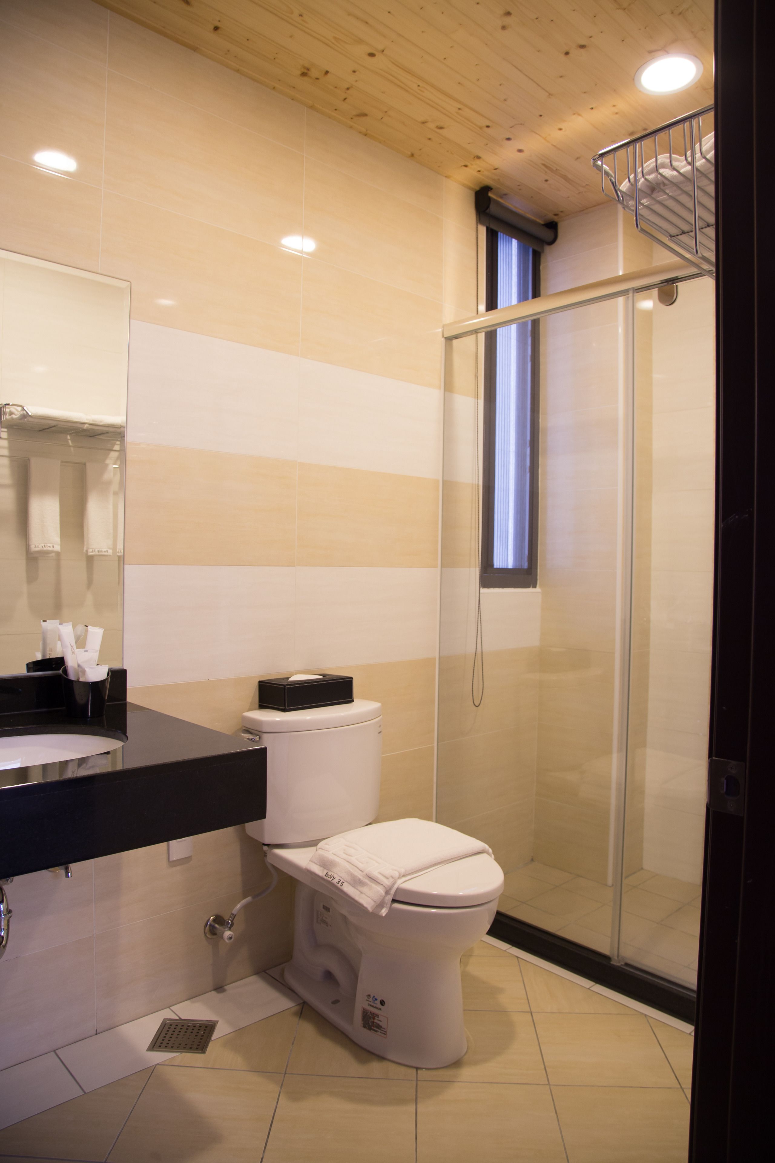 Une salle de bain moderne équipée de toilettes, d’un lavabo et d’une douche à parois de verre.
