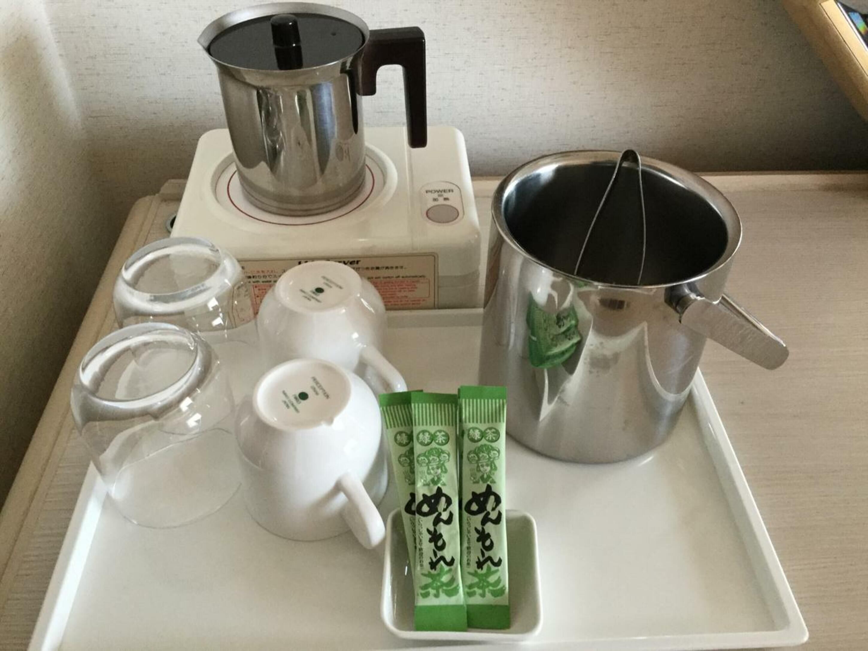 Un plateau avec une bouilloire, une théière, des tasses et des sachets de thé.