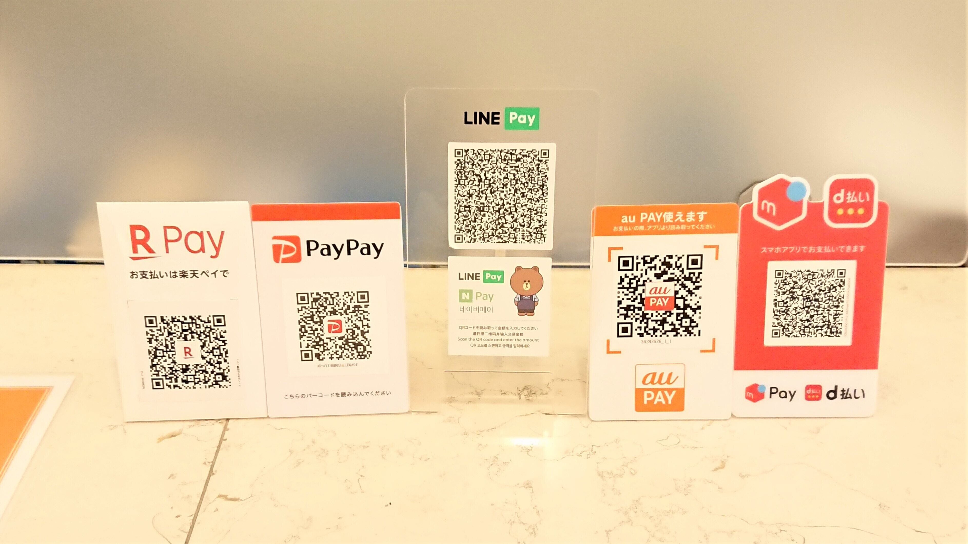 Five payment cards with QR codes and logos for R Pay, PayPay, LINE Pay, au PAY, and a card with a bear logo.