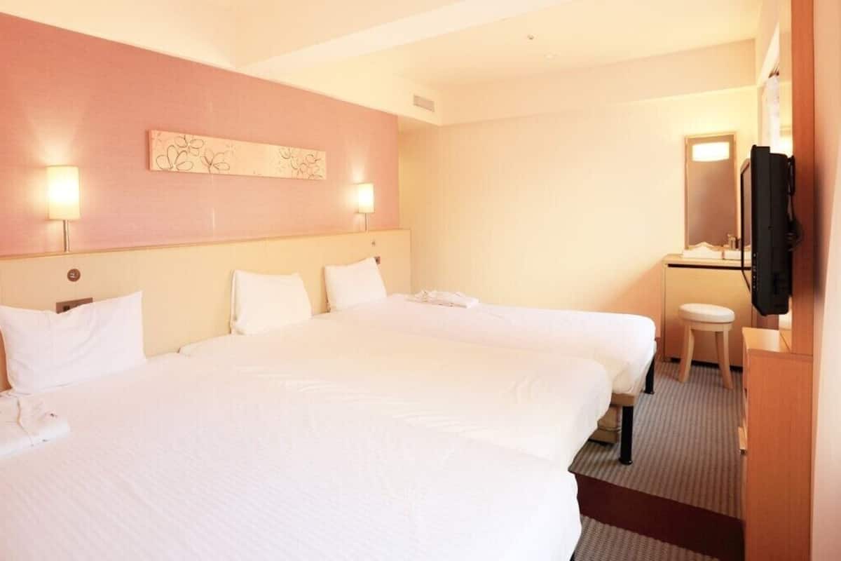 Een hotelkamer met twee bedden, een bureau, een stoel, een televisie en een spiegel.