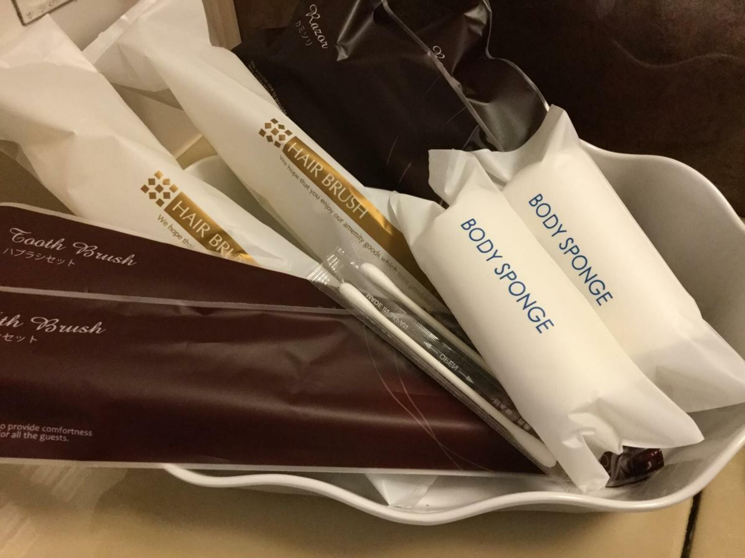 A tray with various toiletries including a toothbrush, hair brush, body sponge, and razor.