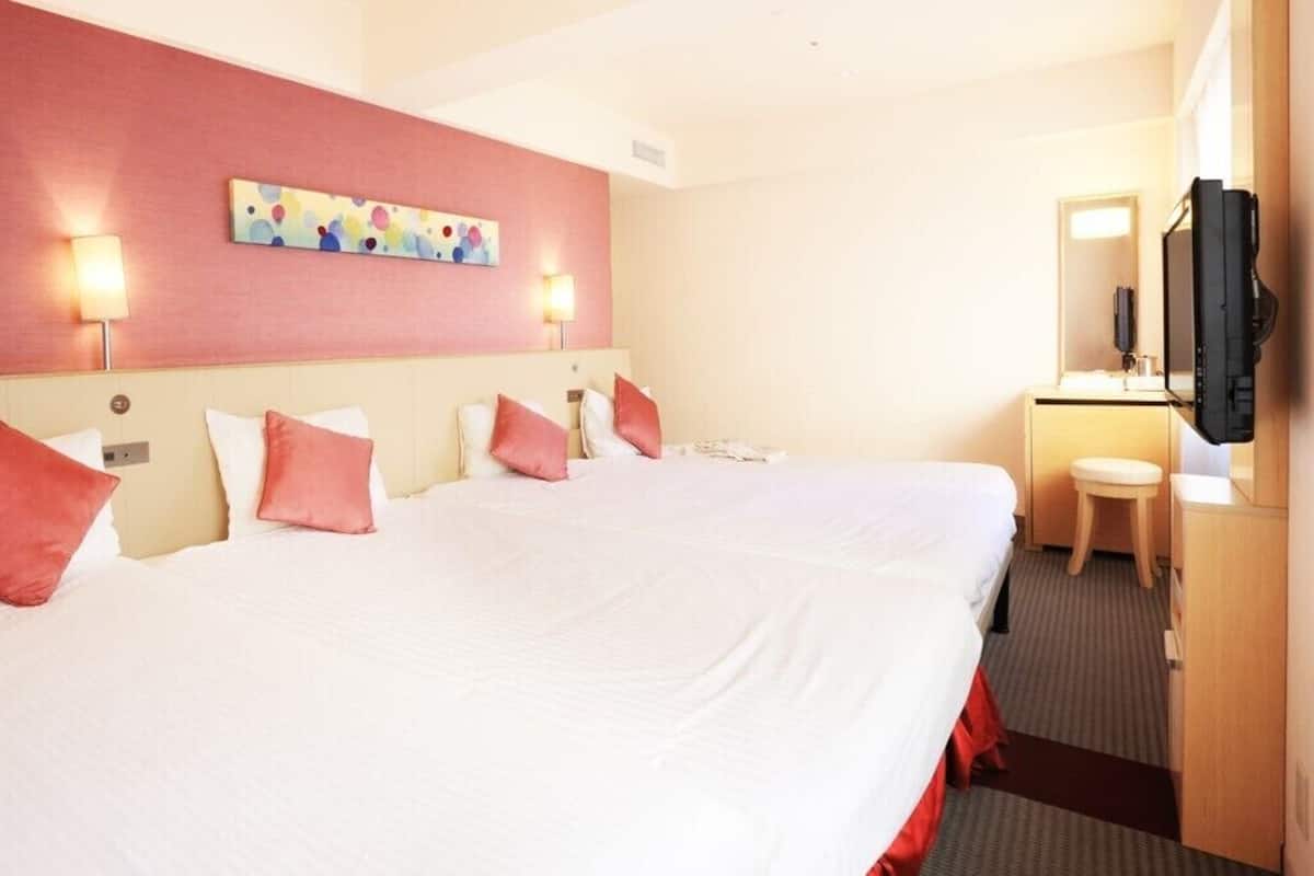 Een hotelkamer met een groot bed, een bureau, een stoel, een televisie en een schilderij aan de muur.