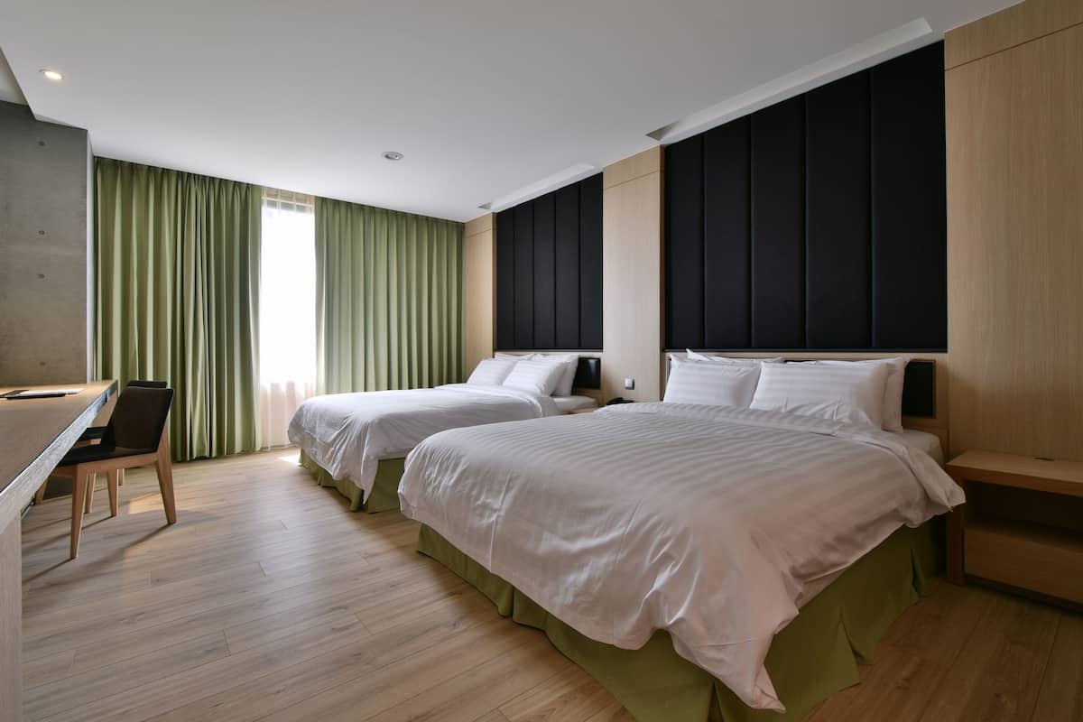 A modern hotel room with two beds, a desk, and a chair.