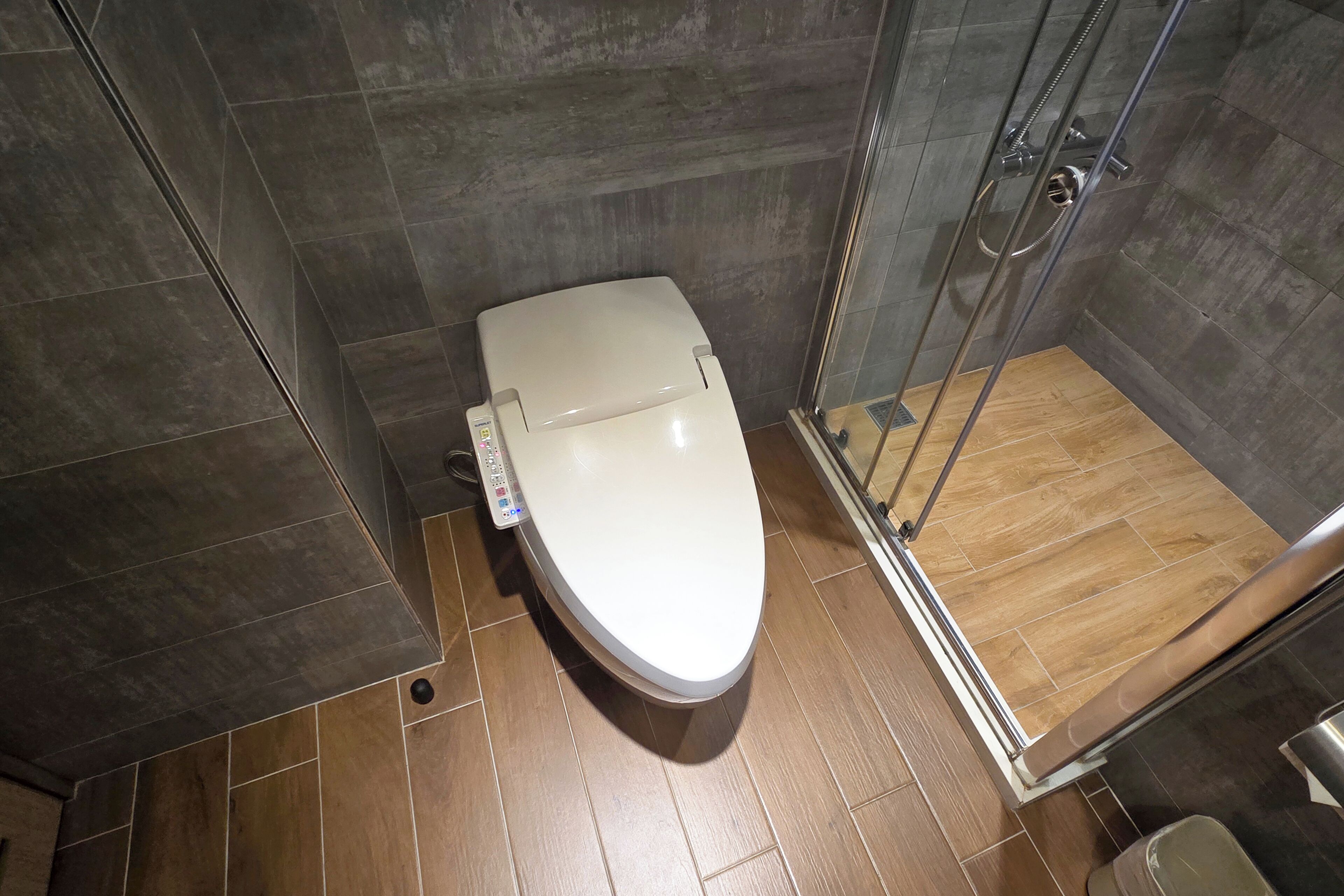 Ein modernes Badezimmer mit Toilette, Duschkabine und Holzboden.