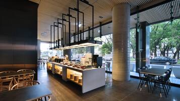 A modern cafe with a central counter, seating area, and large windows.
