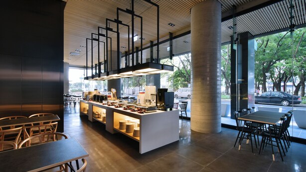 Una cafeteria moderna amb una barra central, zona de seients i grans finestres.