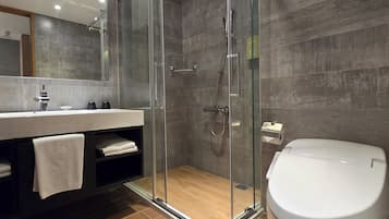 A modern bathroom with a glass-enclosed shower, a white sink, and a toilet.