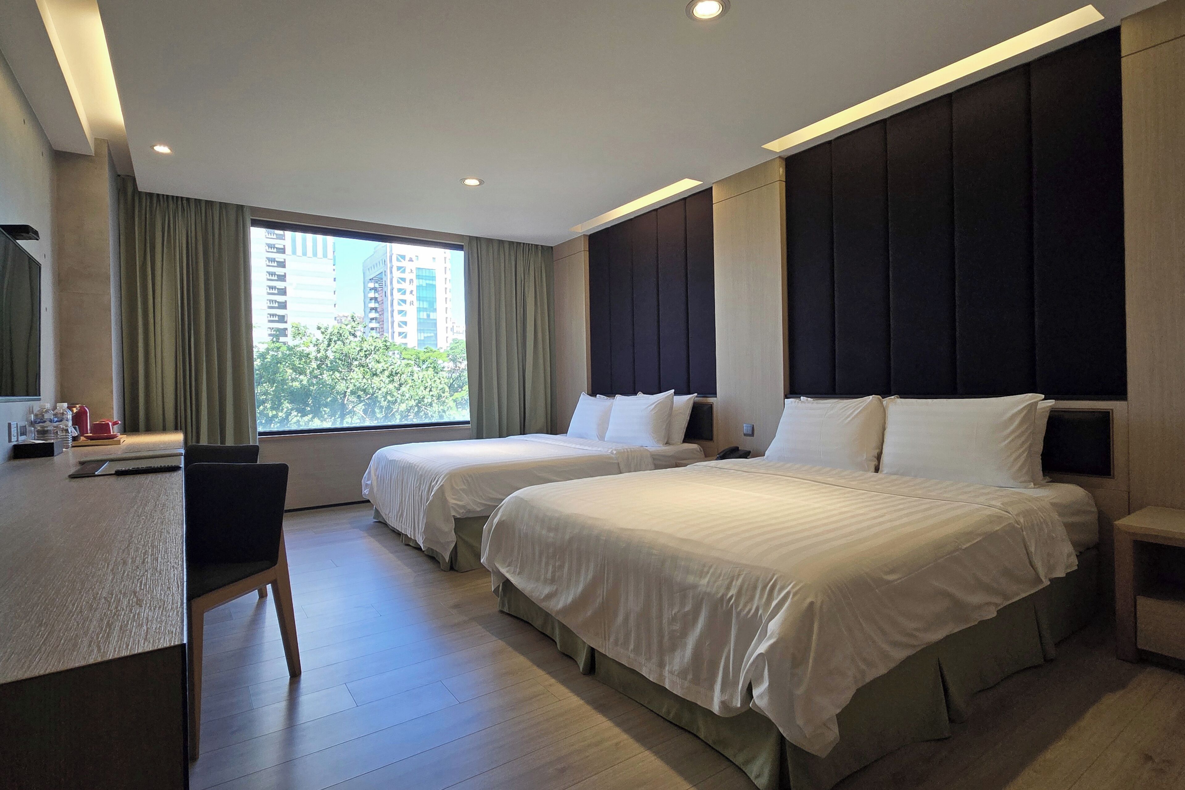 A hotel room with two beds, a desk, and a chair.