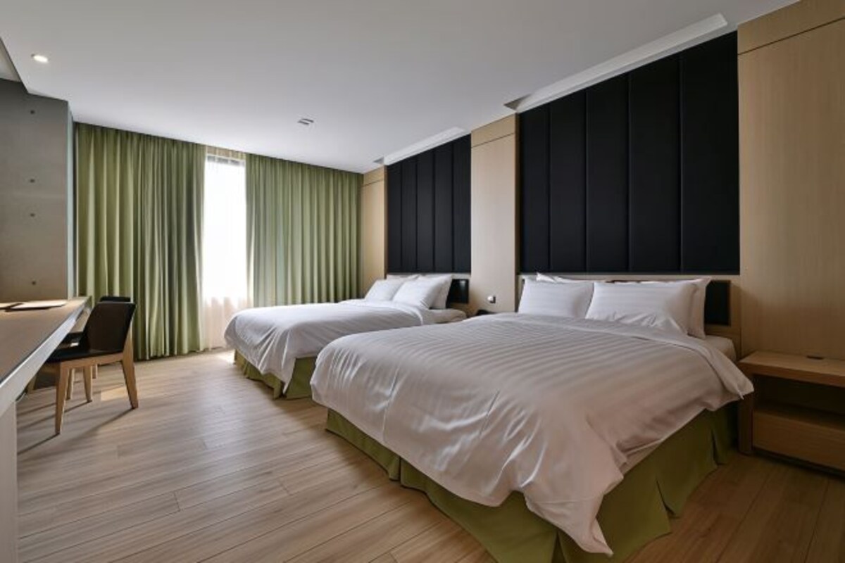 A hotel room with two beds, a desk, and a chair.