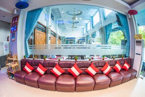 A modern hotel lobby with a curved seating area, large windows, and a view of the dining area. - Diamond Crown Hotel (Yangon)