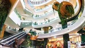 A multi-level shopping mall with escalators, a central atrium with hanging plants, and a bakery. - Diamond Crown Hotel (Yangon)