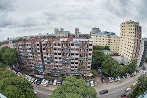 A multi-story building with balconies, surrounded by parked cars and trees. - Diamond Crown Hotel (Yangon)