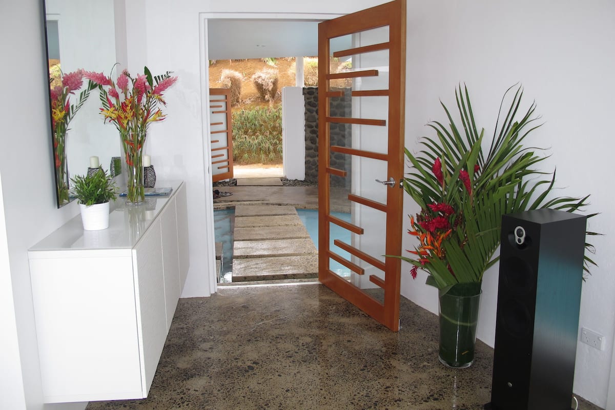 A hallway with a white console table, a mirror, and a potted plant.