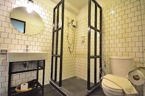A bathroom with white tiled walls, a round mirror, a sink, a toilet, and a shower enclosure. - STrips the Poshtel - Hostel (Chiang Mai)