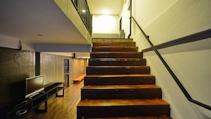 Una escalera de madera con barandilla que lleva a un piso superior.