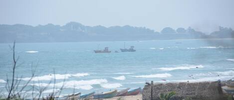 A coastal scene with boats on the water and a beach in the foreground.