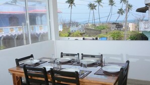 Un comedor con una mesa dispuesta para seis personas, seis sillas y un ventanal con vistas a palmeras y edificios.