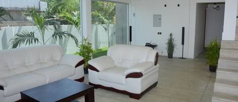 A modern living room with a white sofa, a coffee table, and potted plants.