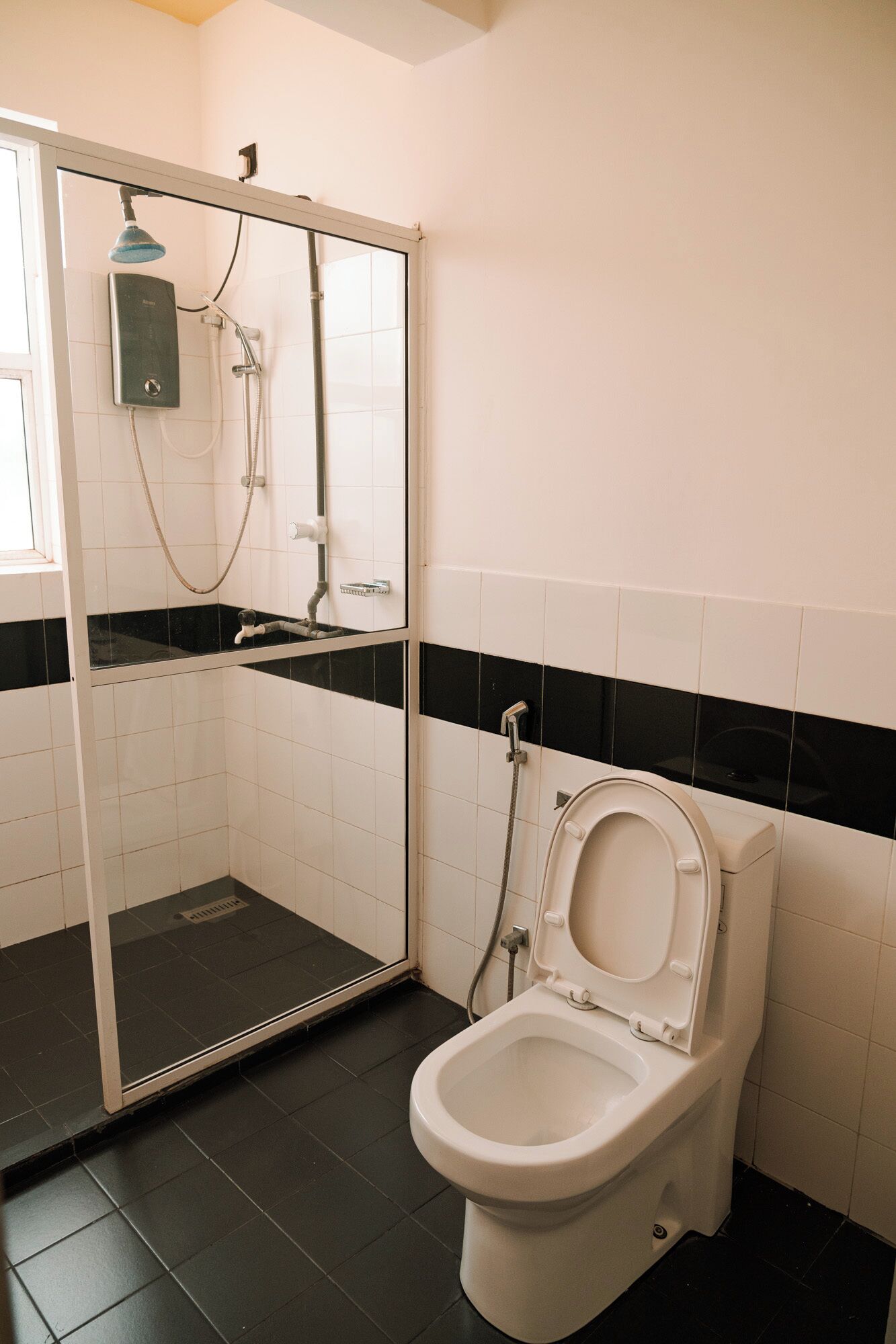 A bathroom with a glass-enclosed shower, a toilet, and a sink.