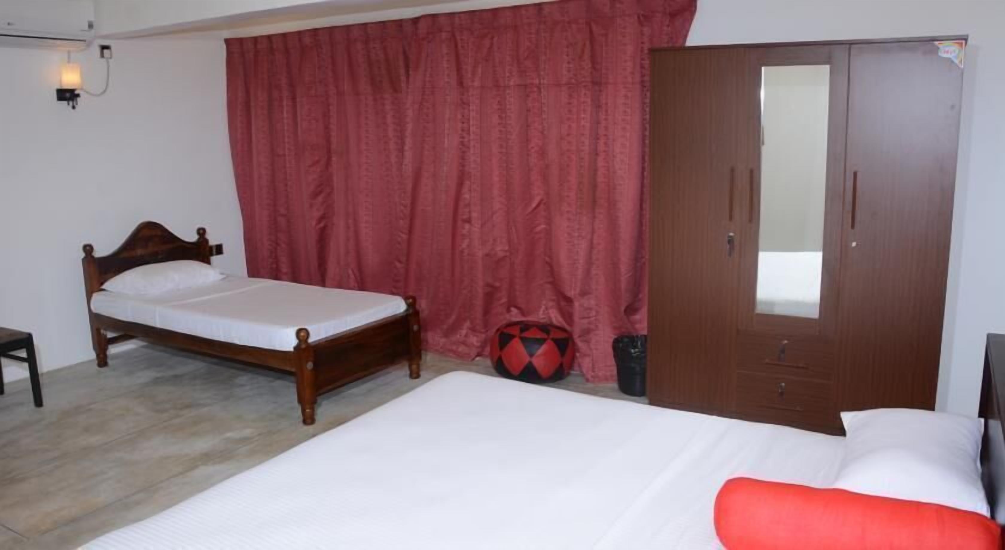 A bedroom with a wooden bed, a wardrobe, and a red curtain.