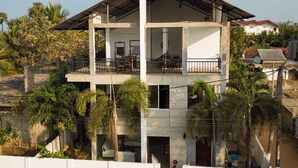 Un edificio de dos pisos con un balcón en el nivel superior, rodeado de palmeras.