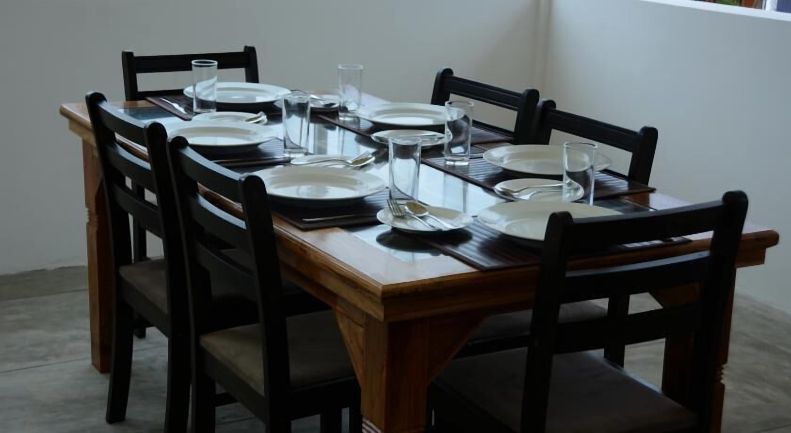 Una mesa de comedor dispuesta con platos, vasos y cubiertos.