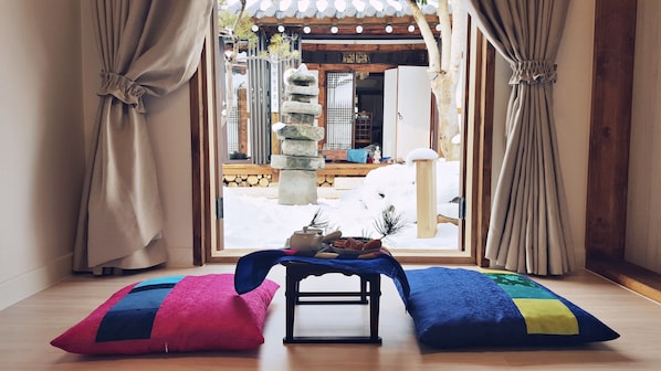 Ein Zimmer mit Blick auf ein traditionelles koreanisches Tor, einen Stein Laternen und einen Holztisch mit Kissen.