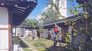 Ein traditioneller koreanischer Innenhof mit Holzbauten, Steinlaternen und einem gepflegten Garten.