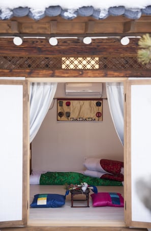 Ein gemütliches Zimmer mit Bett, Kissen, einem kleinen Tisch und einer Wanddekoration.