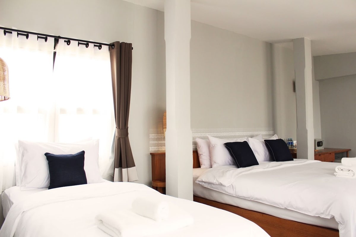 A hotel room with two beds, white bedding, and a view of a cityscape.