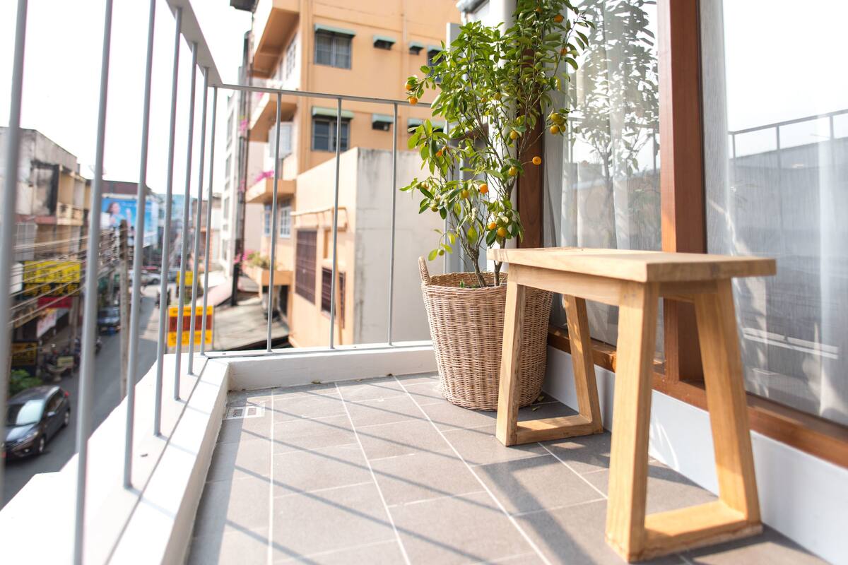 A balcony with a wicker basket, a wooden stool, and a potted plant.