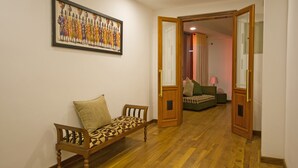 A hallway with a wooden bench, a framed artwork on the wall, and an open door leading to a room with a bed and a lamp. - Hill Pride City Hotel (Nuwara Eliya)