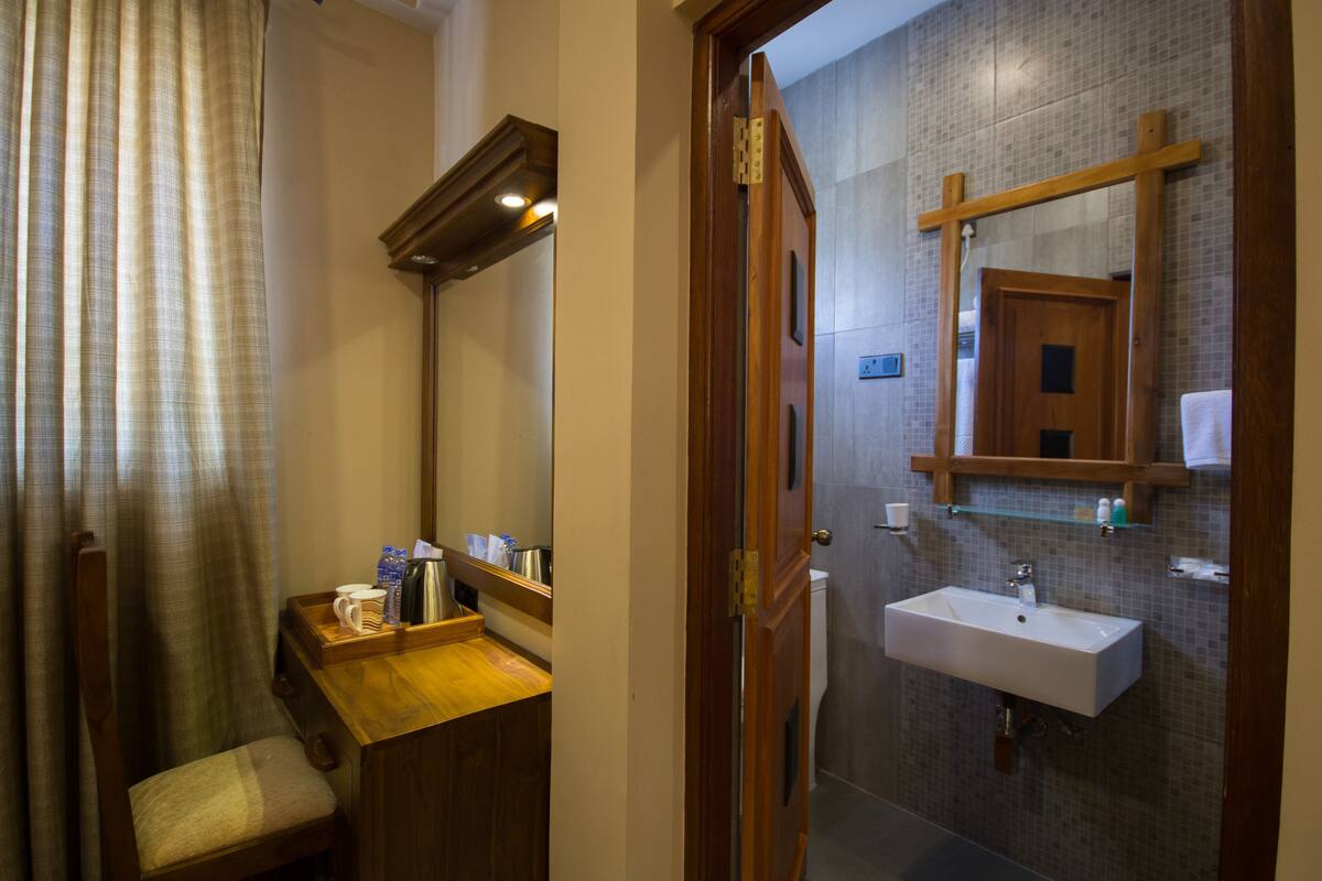 Un baño con tocador de madera, un lavamanos y un espejo.