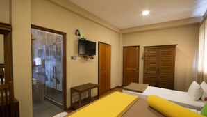 A hotel room with a bed, a small table, a TV mounted on the wall, and a wooden wardrobe. - Hill Pride City Hotel (Nuwara Eliya)