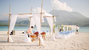 A beach wedding setup with a canopy, chairs, and a table. - Paras Beach Resort (Mambajao)
