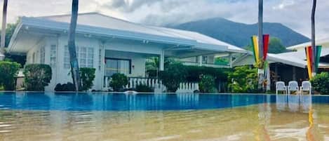 A resort with a swimming pool, white buildings, and palm trees.