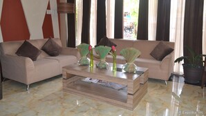 A living room with a beige sofa, a coffee table with magazines, and decorative vases.
