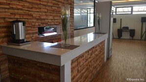 A reception desk with a brick wall, a coffee maker, and a vase with flowers.