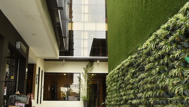 A modern building with a tiled floor, a green wall with plants, and a signboard.