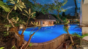 A swimming pool with a thatched-roof hut, surrounded by tropical plants. - Jimbaran Bay Beach Resort & Spa (Kedonganan)