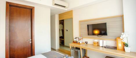 A hotel room with a bed, a desk with a television, and a wardrobe.