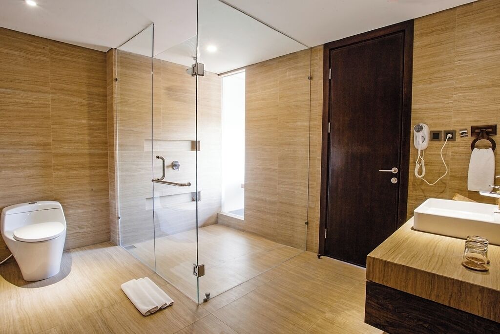 Un baño moderno con cabina de ducha de vidrio, tocador de madera y puerta oscura.